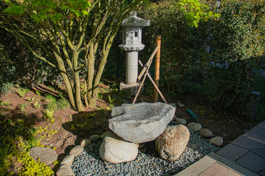 A japanese garden with stone features and lantern.