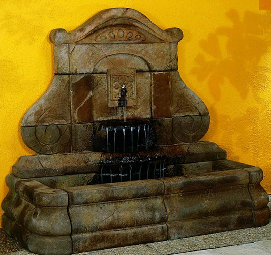 Avignon Fleur De Lys Wall Outdoor Fountain in a garden setting
